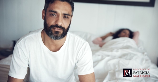 Hombre en la cama mirando a la cámara mientras piensa en divorciarse