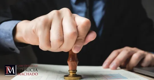 A person in a business suit using a wooden hand stamp to mark a document.