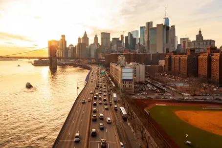 A wide-angle sunset view of the New York City skyline, the Brooklyn Bridge.