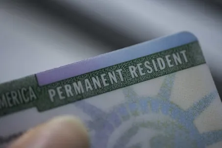 A U.S. Permanent Resident Card, clearly showing the green textured "PERMANENT RESIDENT" header.